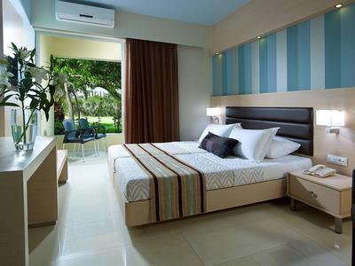Modernes Hotelzimmer mit Doppelbett, schlichter Einrichtung und Blick auf Terrasse und Garten.