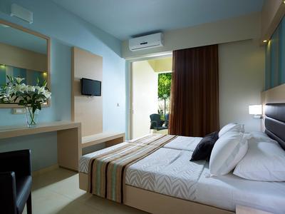 Modern eingerichtetes Hotelzimmer mit Doppelbett, TV und Balkon mit Blick ins Grüne.