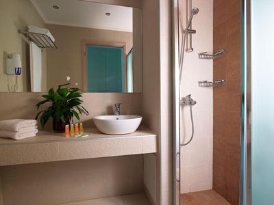 Modernes Hotelbadezimmer mit Waschbecken, Handtüchern, Pflegeprodukten und begehbarer Dusche.