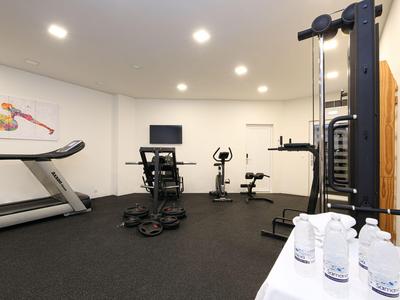 Moderner Fitnessraum mit Laufband, Fahrrädern und Trainingsgeräten in Hotelumgebung.