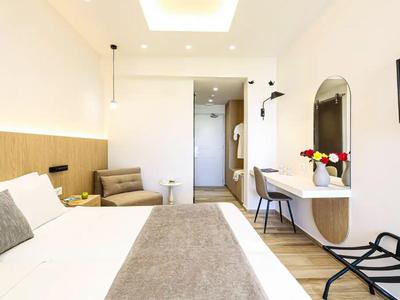 Modernes Hotelzimmer mit großem Bett, Schreibtisch, Sitzbereich und minimalistischer Dekoration.