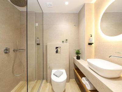 Modernes Badezimmer mit begehbarer Dusche, Toilette und Waschbecken auf hellem Holz.