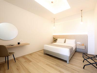 Helles Hotelzimmer mit Doppelbett, Schreibtisch und Holzboden unter natürlichem Licht.
