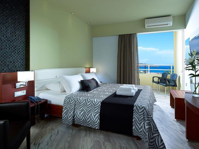 Hotelkamer met tweepersoonsbed, balkon met uitzicht op zee en moderne inrichting.