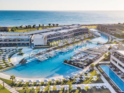 Luxuriöses Hotelresort mit großem Poolbereich und Meerblick bei Sonnenuntergang