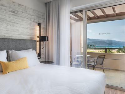 Modernes Hotelzimmer mit Doppelbett und Balkon mit Bergblick.