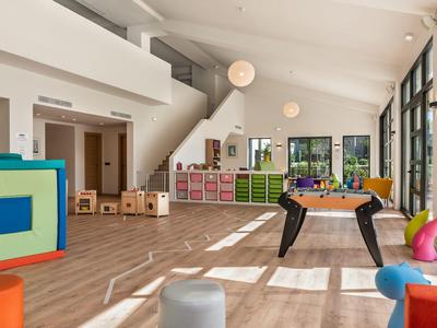 Bright playroom with toys, storage units, foosball table and large windows.