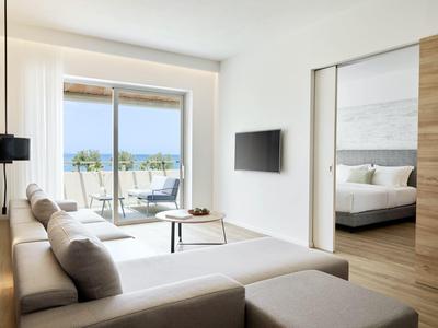 Modern living room with sofa, TV, and balcony view overlooking the sea.