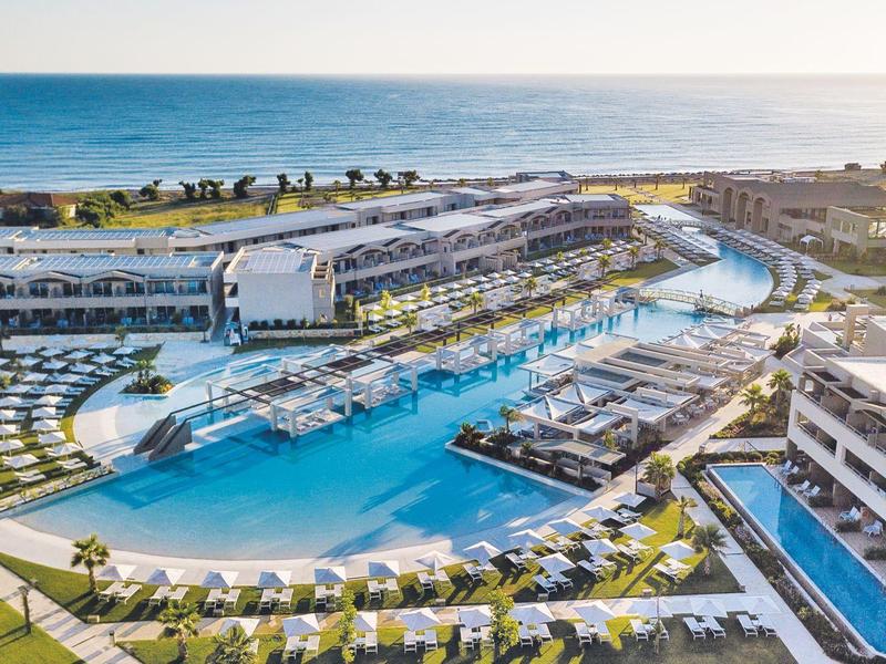Aerial view of a large resort featuring pools, sunbeds, and a sea view.