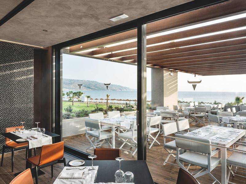 Modern dining area with indoor and outdoor seating overlooking a scenic water view.