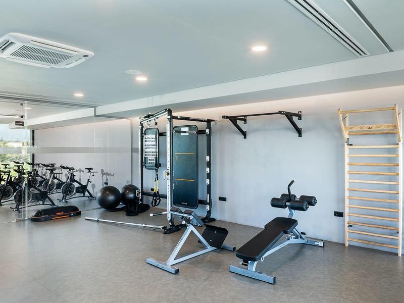 Modern hotel gym with exercise bikes, weight machines, and workout benches.