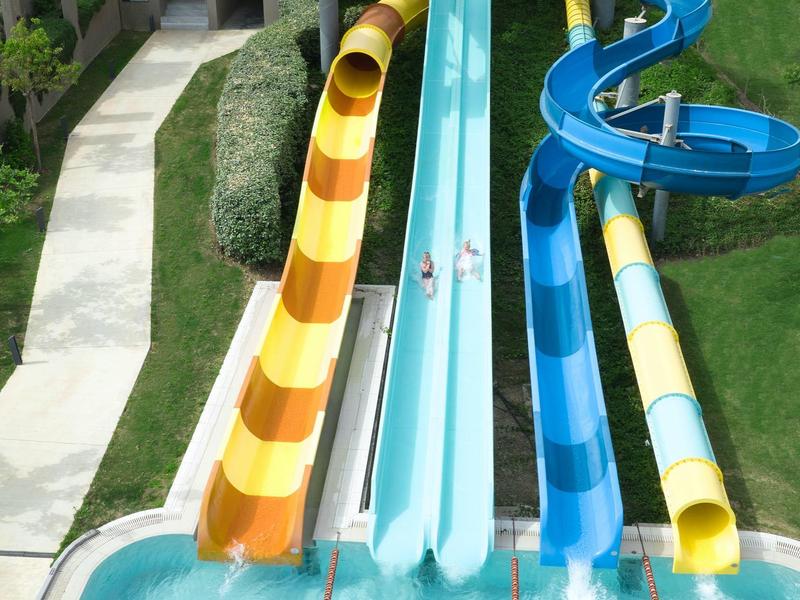Four colorful water slides leading into a pool at a water park.
