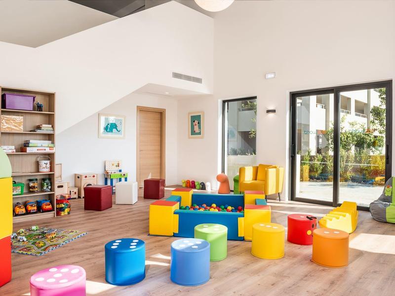 Colorful children's play area with large windows and wooden floor in a bright room.