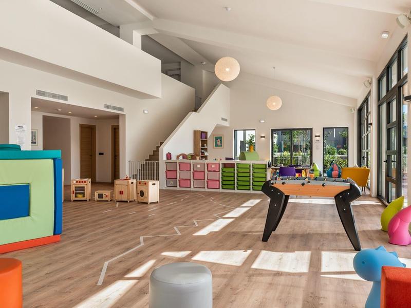 Bright playroom with toys, storage units, foosball table and large windows.