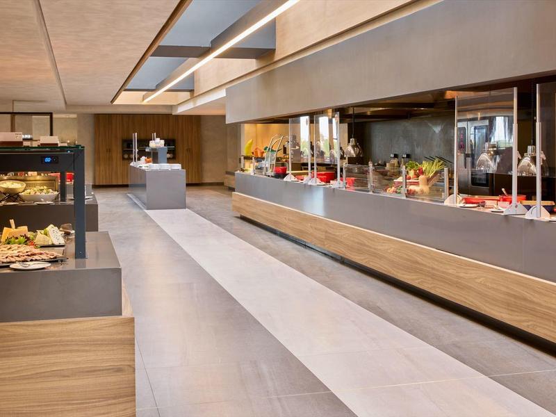 Modern hotel buffet with a variety of breakfast items displayed in a sleek, spacious area.