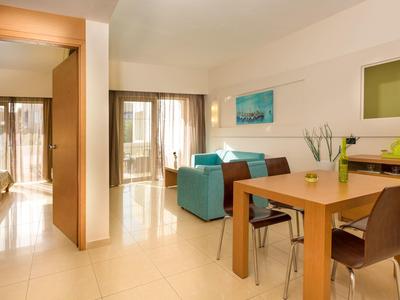 Světý obývací prostor s jídelním stolem, pohovkou a přístupem na balkon v moderním rekreačním bytě.