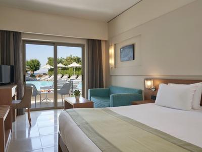 Camera d'hotel moderna con letto, divano, TV e vista sulla piscina.