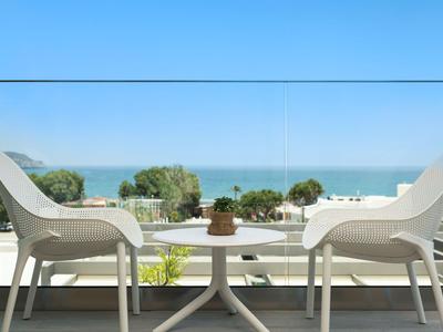 Due sedie bianche su una terrazza con vista sul mare e cielo azzurro.