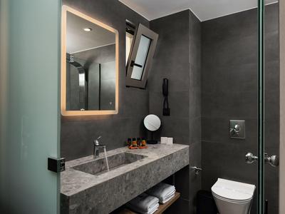 Bagno moderno con pareti grigie, specchio illuminato, lavabo e WC.