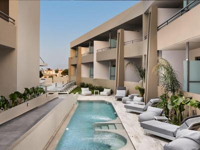 Piscina moderna dell'hotel con lettini e piante tra due edifici.