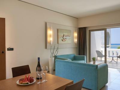 Soggiorno moderno con divano turchese, zona pranzo e balcone con vista mare.