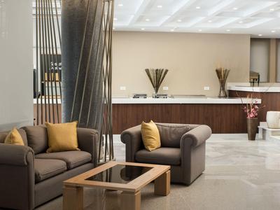 Area lounge dell'hotel moderna con divani, tavolo ed elementi decorativi.