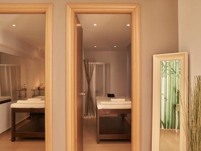 Due bagni con lavandini e specchi in una camera d'albergo, accanto a uno specchio e erba decorativa.