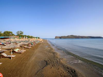 Lettini sulla spiaggia sabbiosa con mare calmo e cielo azzurro limpido.