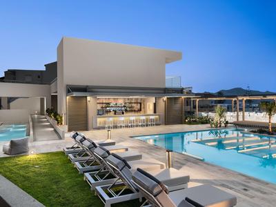 Area piscina moderna dell'hotel con lettini e bar sotto un cielo terso