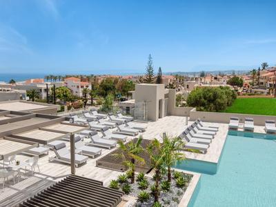 Espace extérieur moderne avec piscine, chaises longues et vue sur la ville et la mer