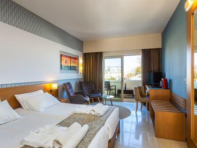 Moderní hotelový pokoj s manželskou postelí, posezením a balkonem s výhledem.