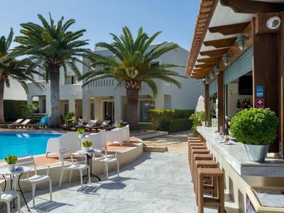 Zone de piscine d'hôtel avec bar, chaises et palmiers par une journée ensoleillée.