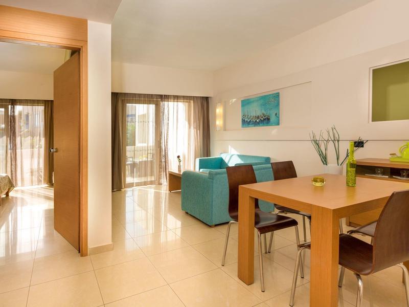 Světý obývací prostor s jídelním stolem, pohovkou a přístupem na balkon v moderním rekreačním bytě.