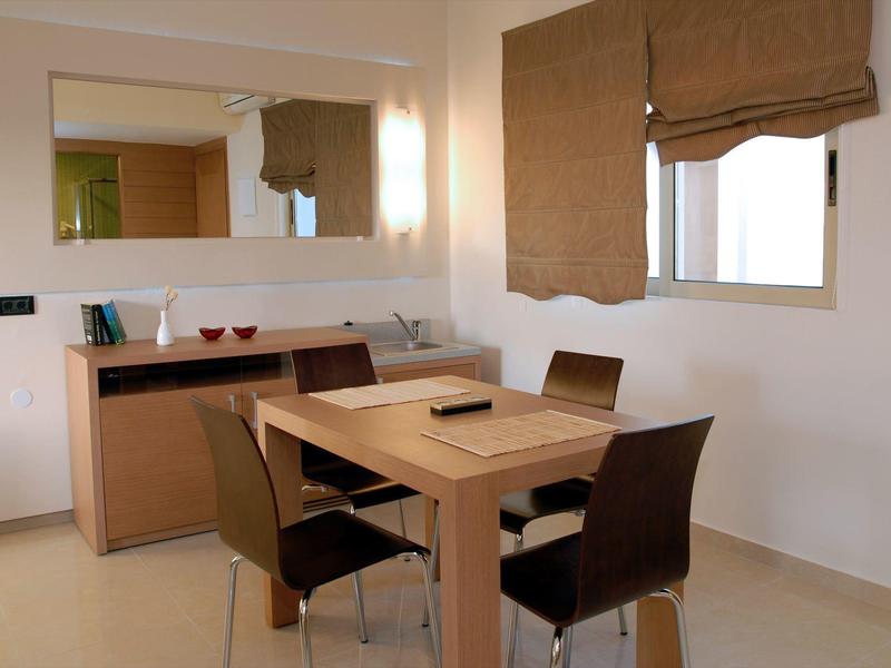 Jídelní kout se stolem a čtyřmi židlemi vedle okna s hnědými závěsy.