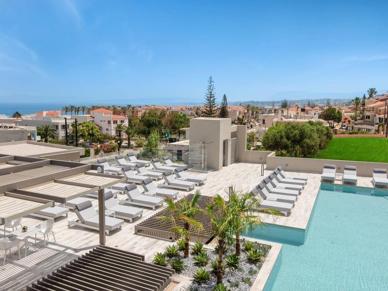 Moderní hotel s bazénem, lehátky a výhledem na město a moře.