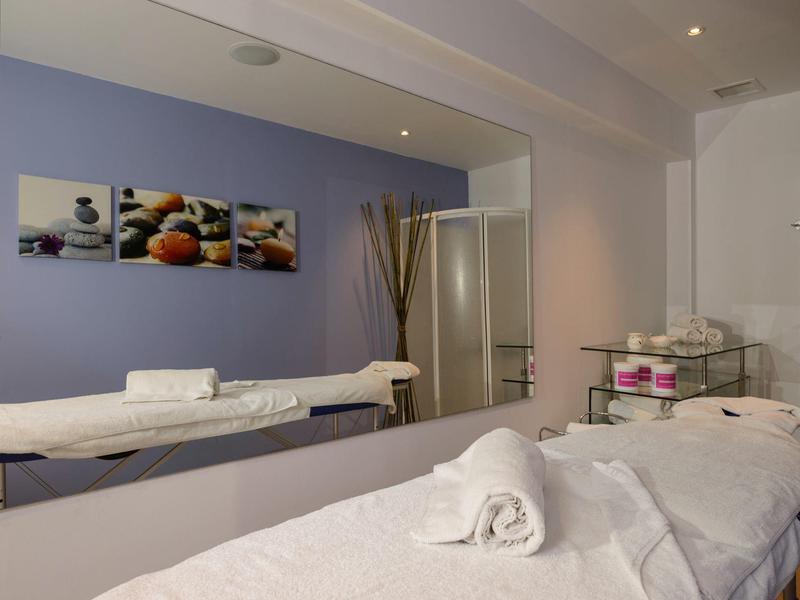 Léčební místnost s masážním stolem, ručníky a uklidňujícími nástěnnými dekoracemi.