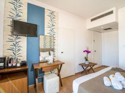 Une chambre d'hôtel moderne avec un lit double, une télévision murale et une petite table avec des fleurs.