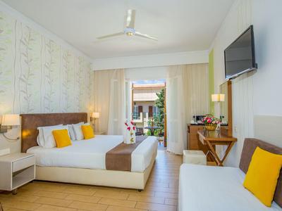 Chambre d'hôtel lumineuse avec lit double, canapé, balcon et décoration moderne.