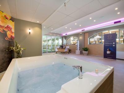 Espace bien-être moderne avec jacuzzi, sièges et éclairage d'ambiance.