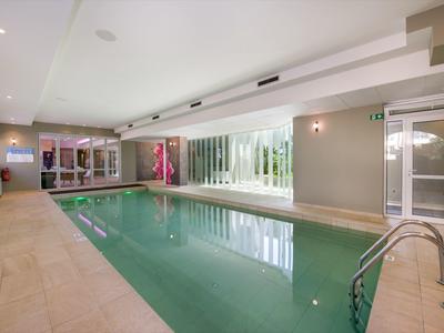 Piscine intérieure moderne avec grandes fenêtres et chaises longues confortables dans un hôtel