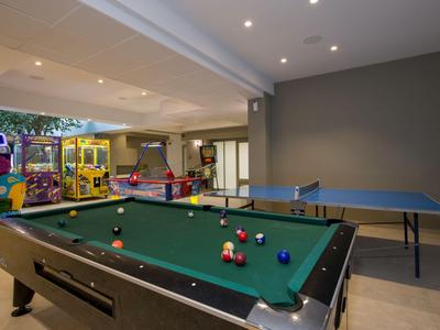 Spielzimmer mit Billardtisch und Tischtennisplatte, moderne Beleuchtung und helle Wände.