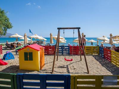 Aire de jeux colorée avec toboggans et balançoires près de la plage sous ciel bleu.