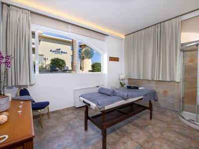 Salle de traitement lumineuse avec un canapé, des fauteuils confortables et une vue sur un hôtel par la fenêtre.