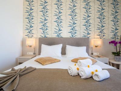 Gemütliches Hotelzimmer mit Doppelbett, dekorativen Kissen und Handtüchern auf brauner Bettdecke.