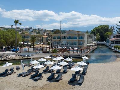 Chaises de plage avec parasols sur plage sablonneuse près de la marina et hôtels sous ciel bleu