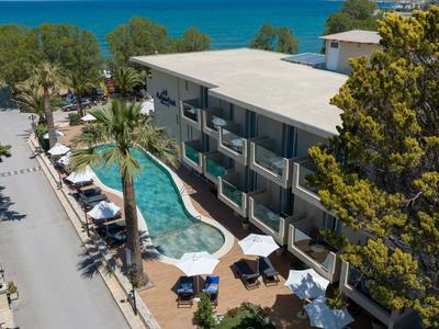 Hotel mit Außenpool und Terrasse nahe dem Meer mit Blick auf Palmen und Liegestühle.