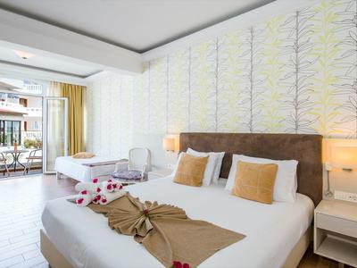 Chambre d'hôtel moderne avec lit double, coussins décoratifs et balcon avec coin salon.