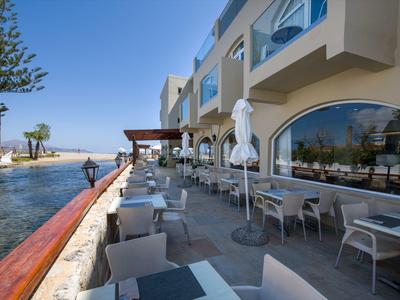 Terrasse extérieure avec tables et chaises à côté d'une piscine et vue sur la mer.