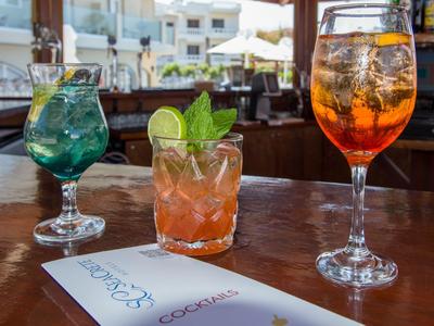 Drei verschiedene Cocktails auf einem Holztisch in einer Bar mit einem Cocktailmenü.