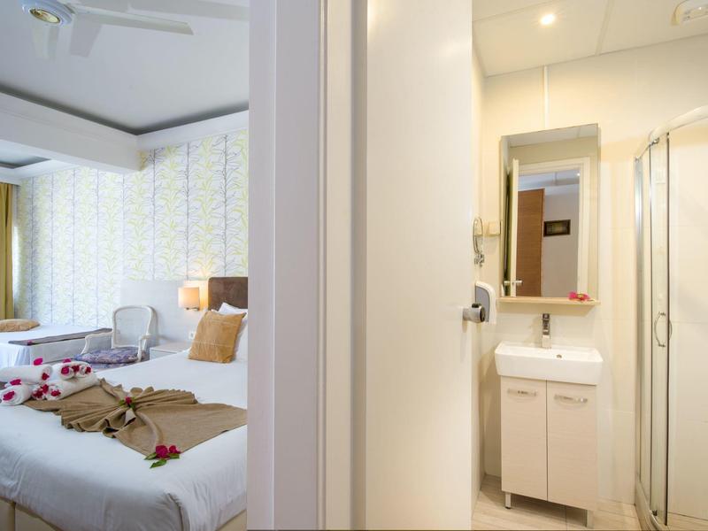 Vue d'une chambre d'hôtel avec deux lits et salle de bains adjacente avec lavabo et douche.